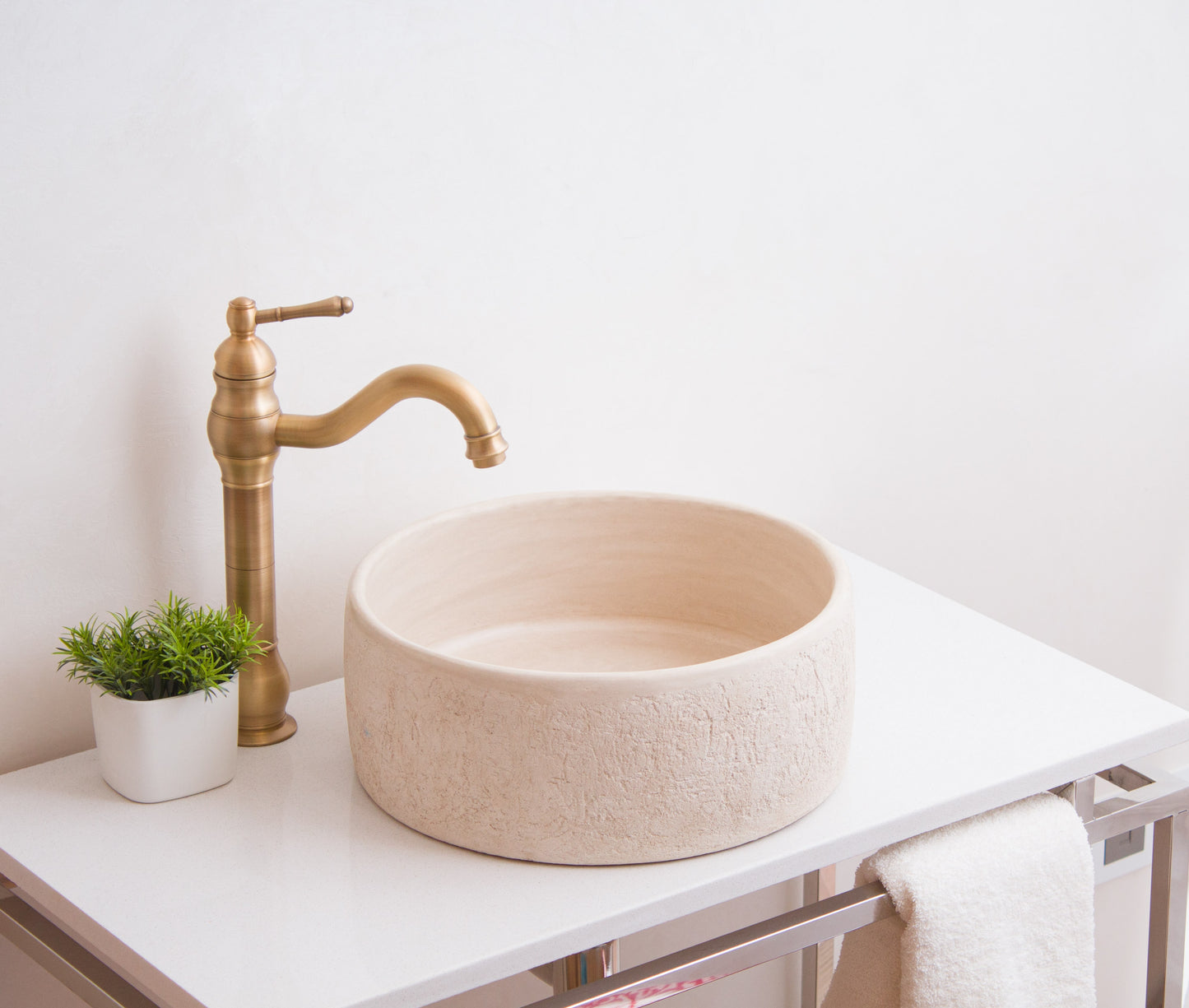Side view of handcrafted ceramic sink with curved brass faucet in modern bathroom setting