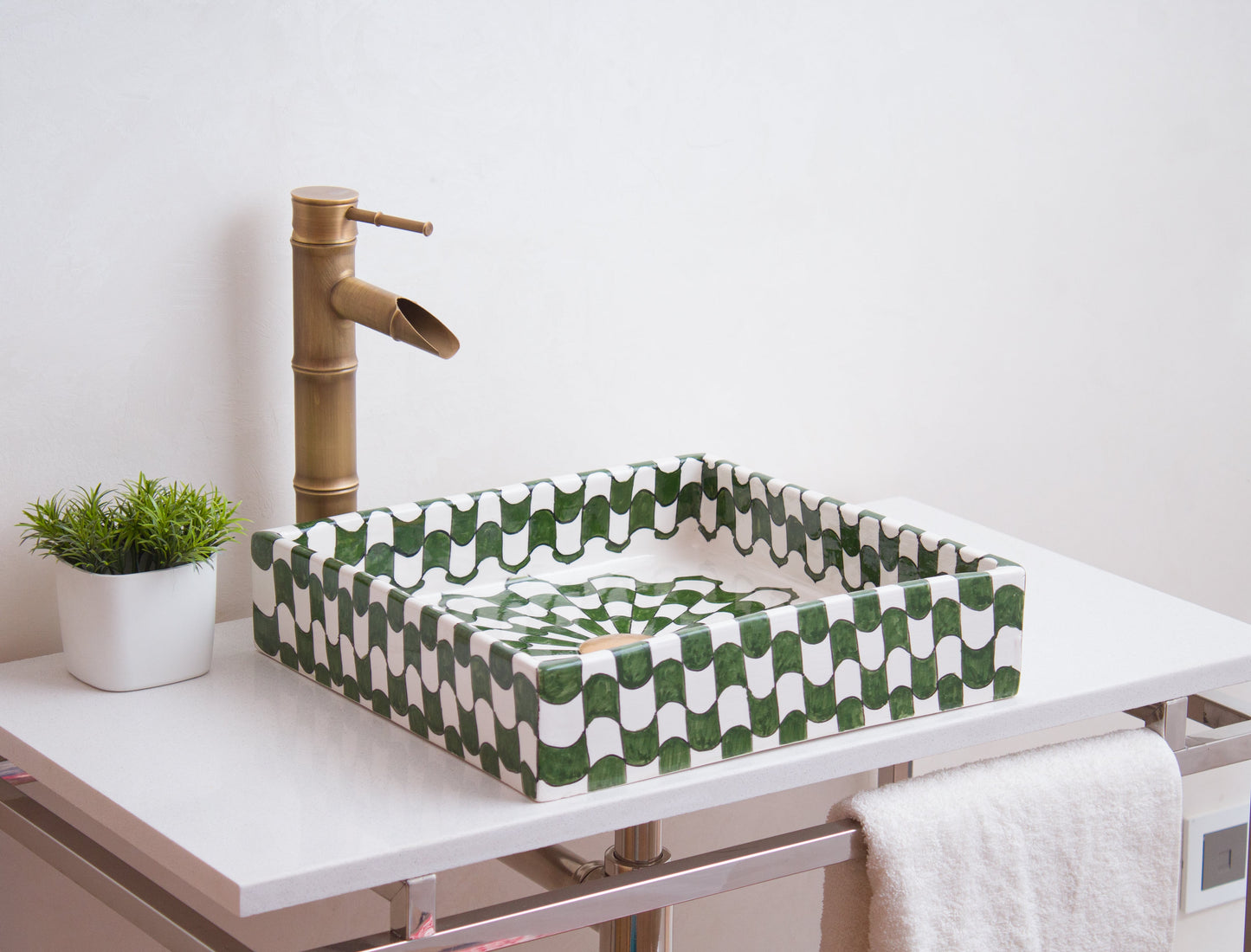 Square Moroccan ceramic basin installed on white bathroom vanity with brass bamboo-style faucet and decorative plant