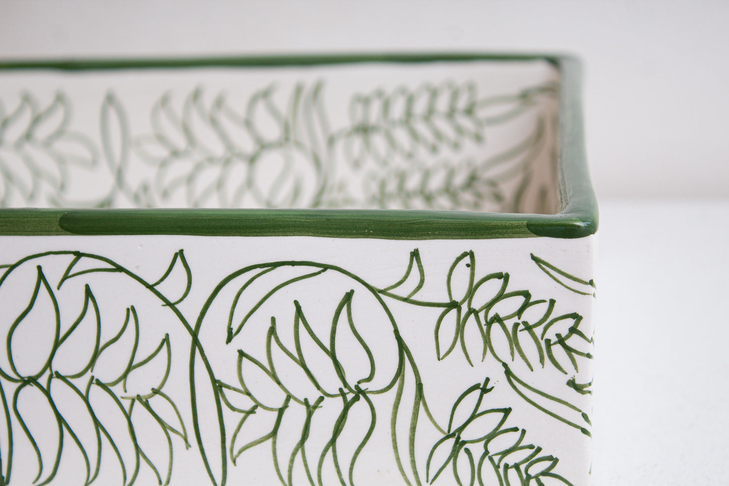 Close-up detail of green hand-drawn botanical motifs and decorative rim on artisan-crafted Moroccan ceramic bathroom basin