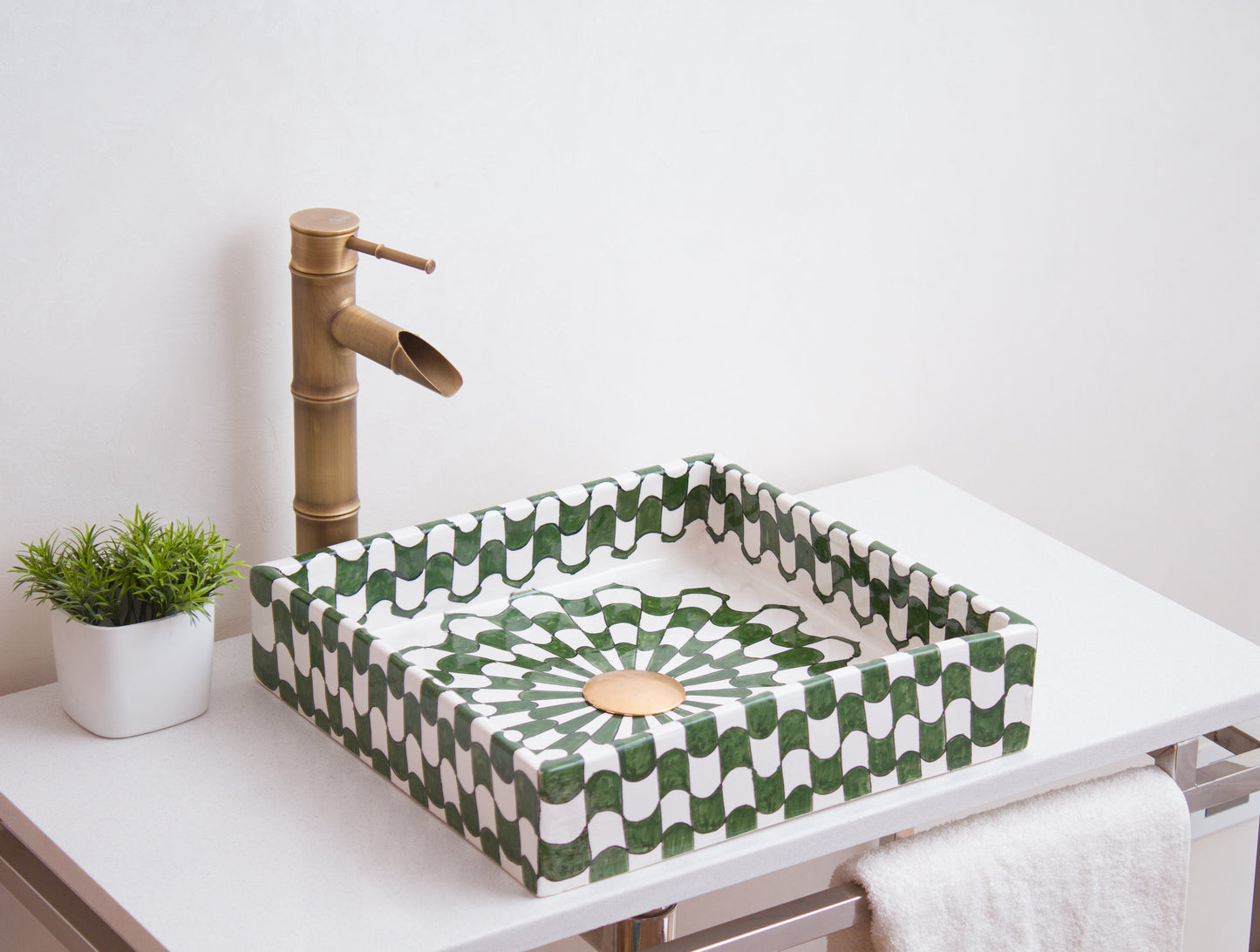 Handmade square ceramic sink positioned on contemporary bathroom counter with traditional brass faucet in modern setting