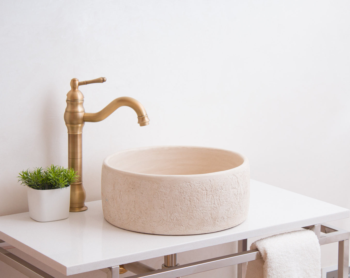Moroccan vessel sink styled on white vanity with brass traditional faucet and plant