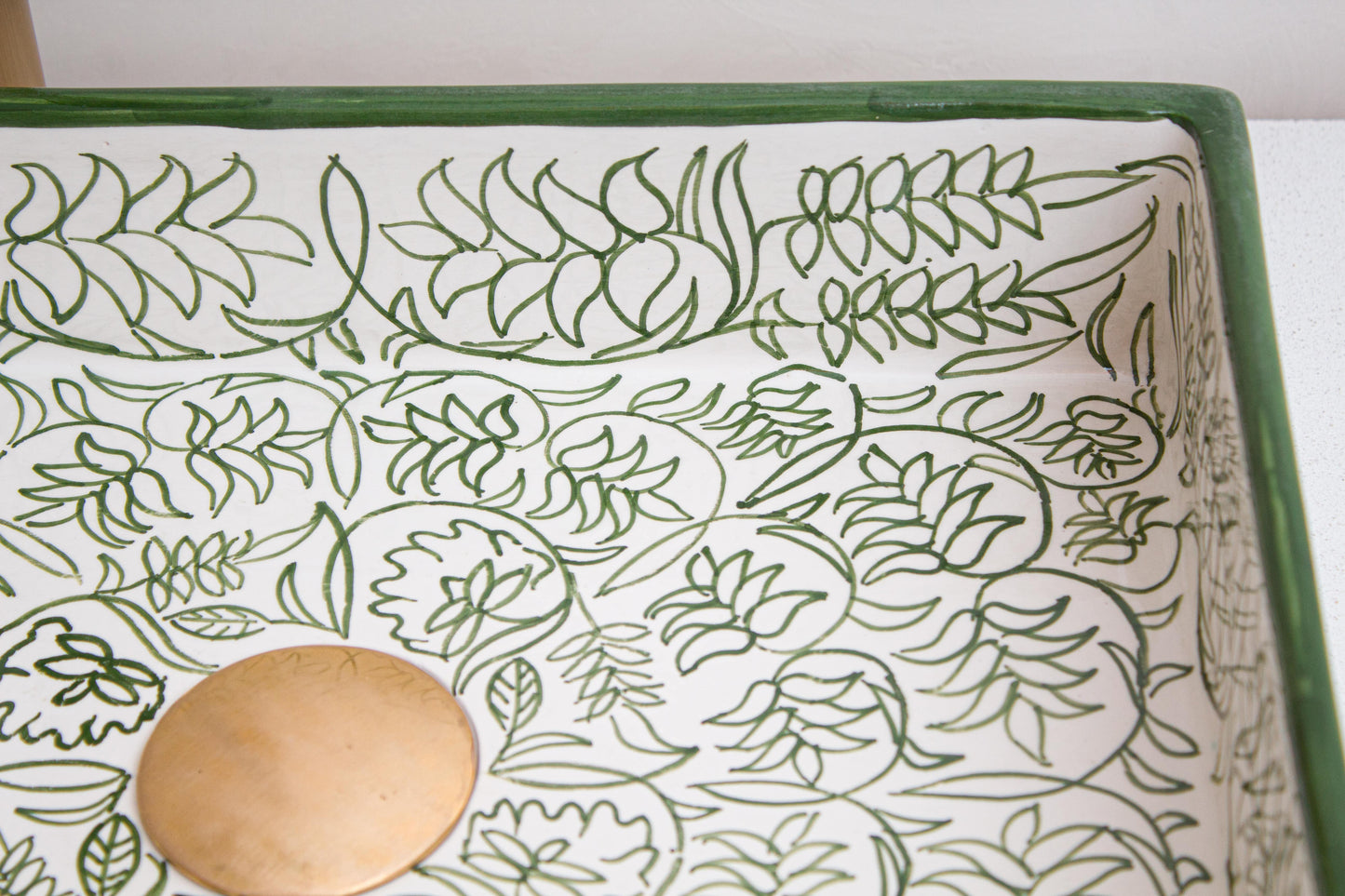 Interior detail view showing intricate floral and leaf patterns with central drain of handcrafted rectangular ceramic vessel sink