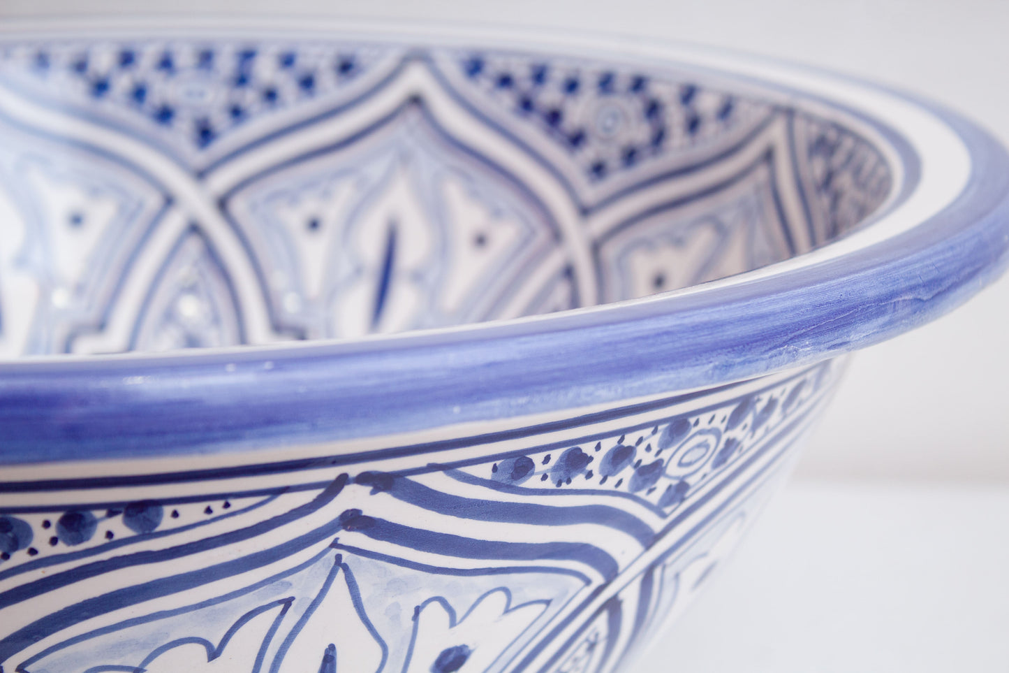 Close-up detail of blue ceramic basin rim showing traditional Moroccan geometric border patterns