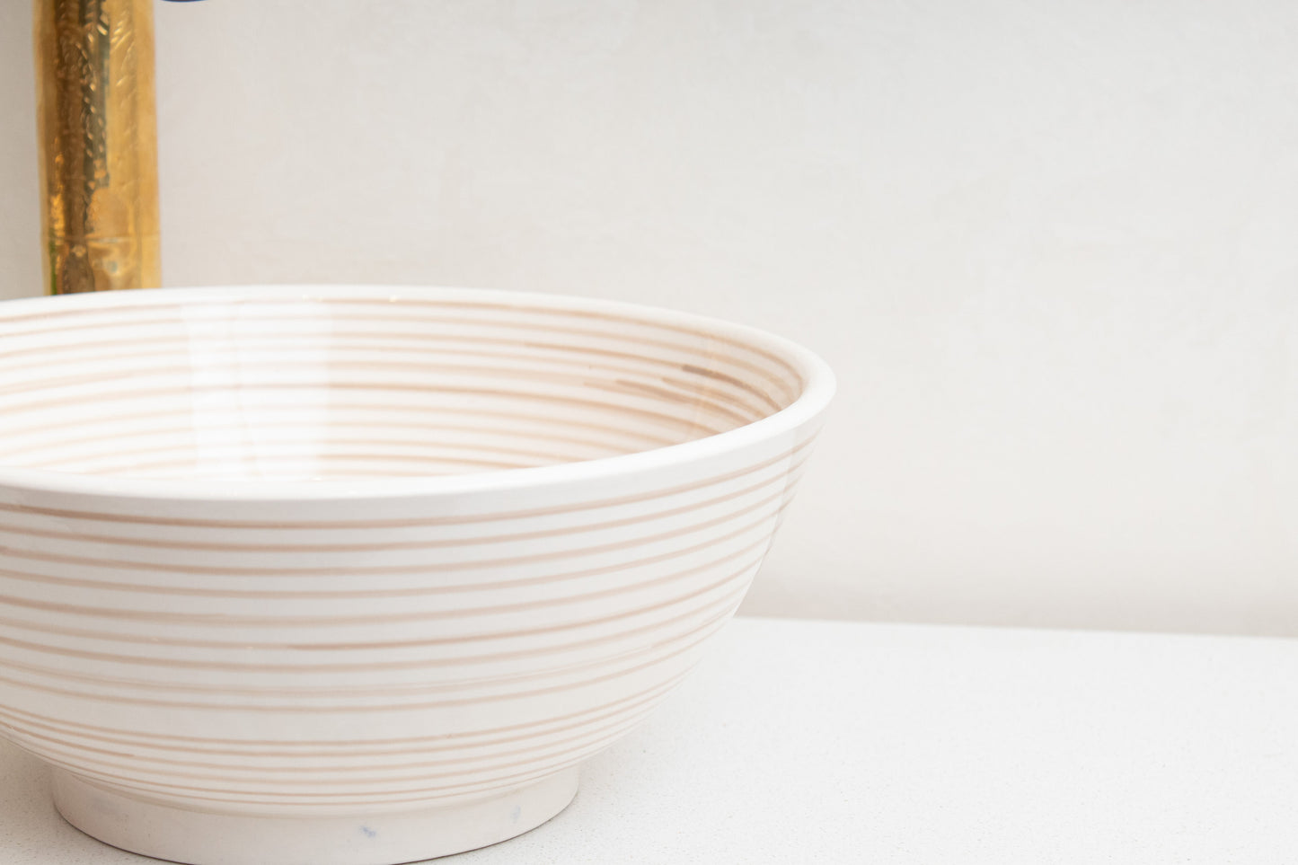 Close-up detail of cream ceramic vessel sink rim and spiral ridged texture highlighting the handcrafted surface pattern