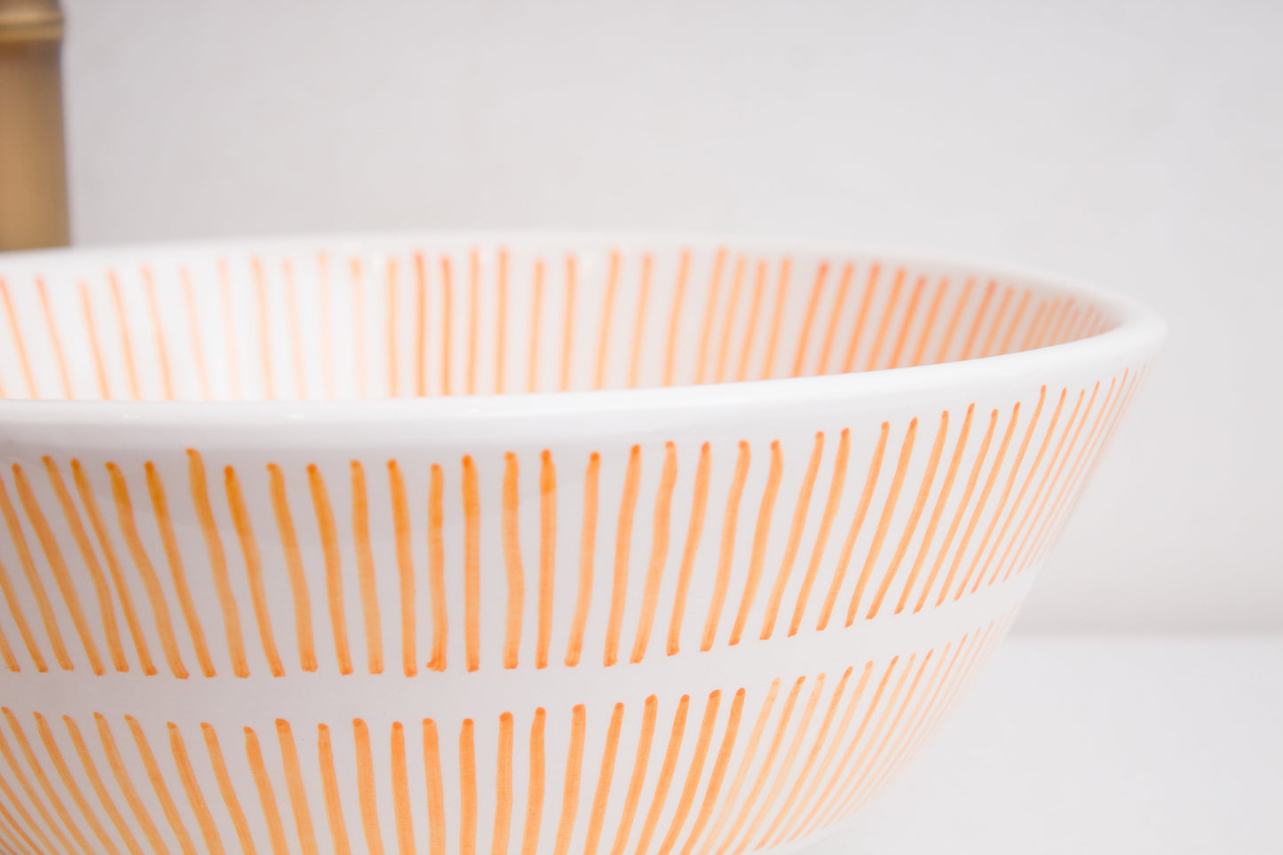 Macro close-up detail of orange radial sunburst line pattern around the exterior rim of handcrafted ceramic basin