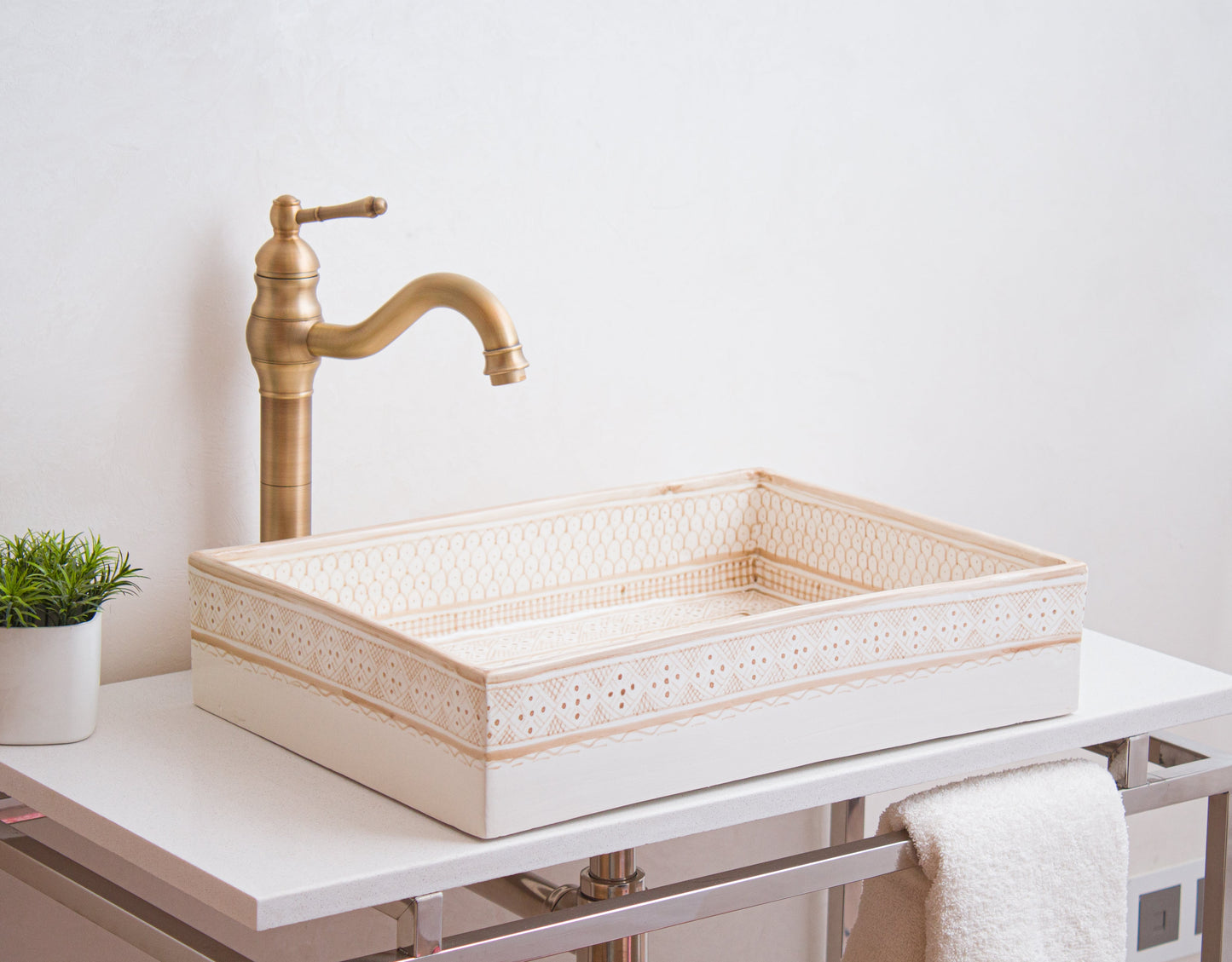 Cream ceramic basin with geometric border styled with brass traditional faucet on modern white vanity