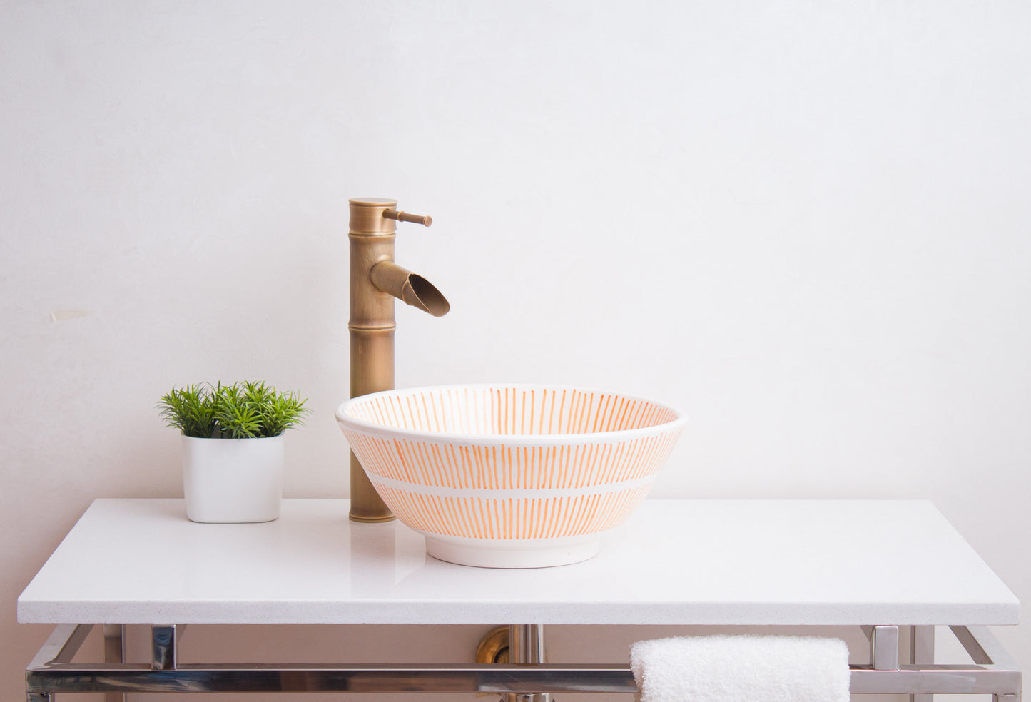 Side profile view of round ceramic vessel sink showing orange sunburst radial line patterns and bathroom installation