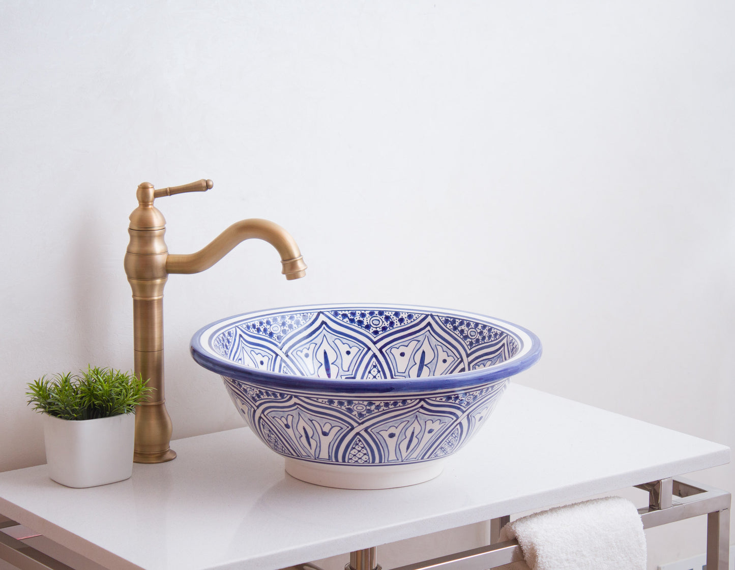 Blue and white ceramic basin styled with brass traditional faucet and decorative plant on modern vanity