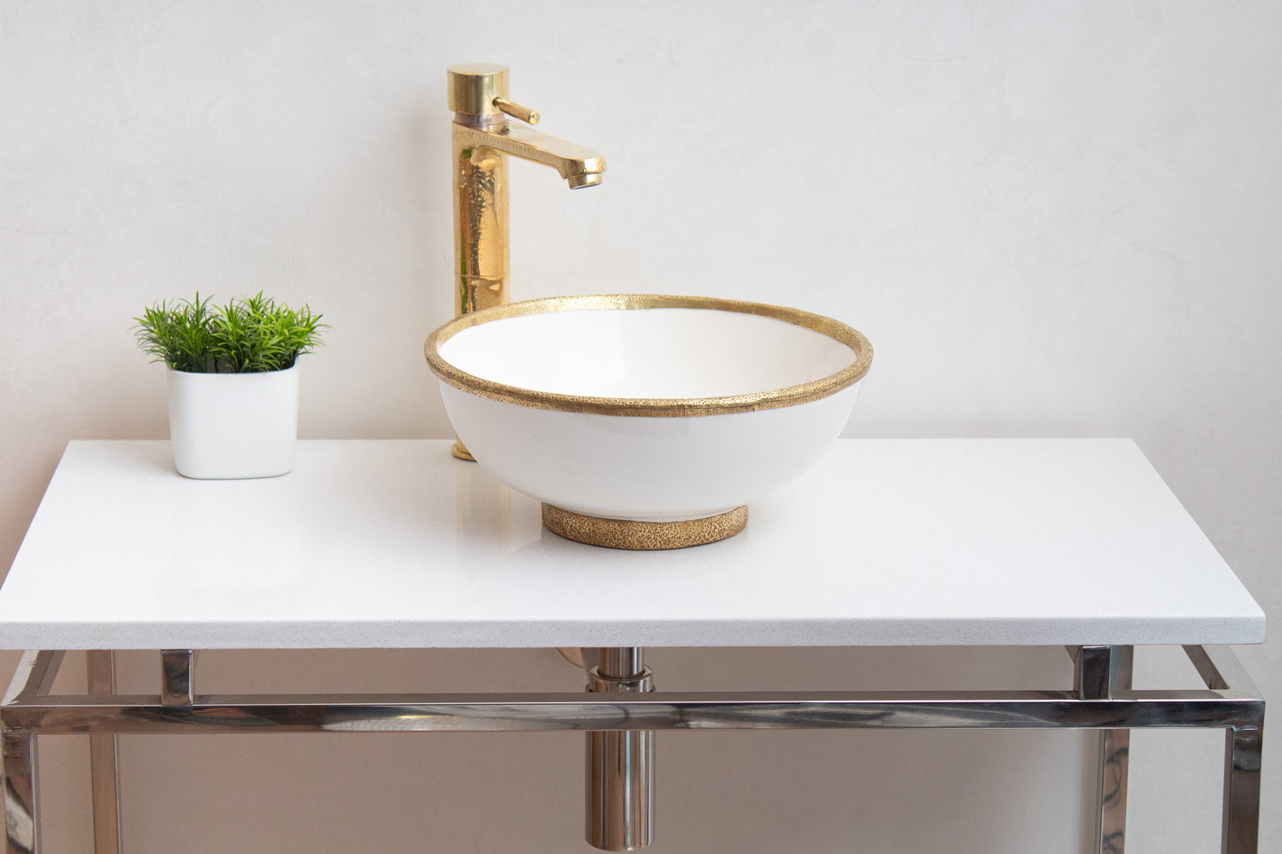 Handcrafted Moroccan white ceramic bowl sink on a marble counter and a brass faucet - front view