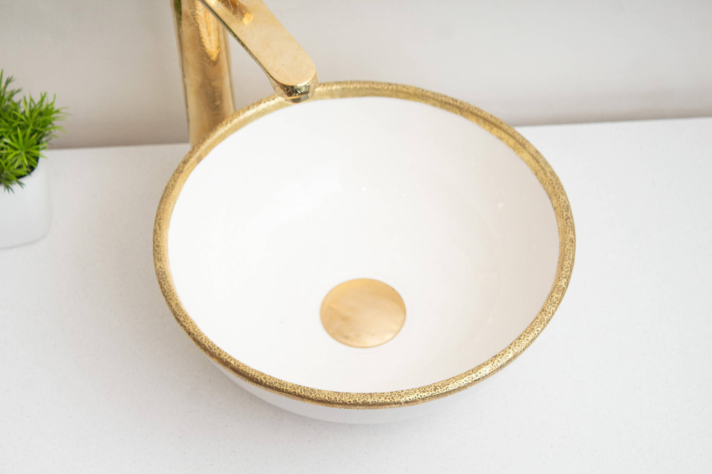 Handcrafted Moroccan white ceramic bowl sink on a marble counter and a brass faucet - top view