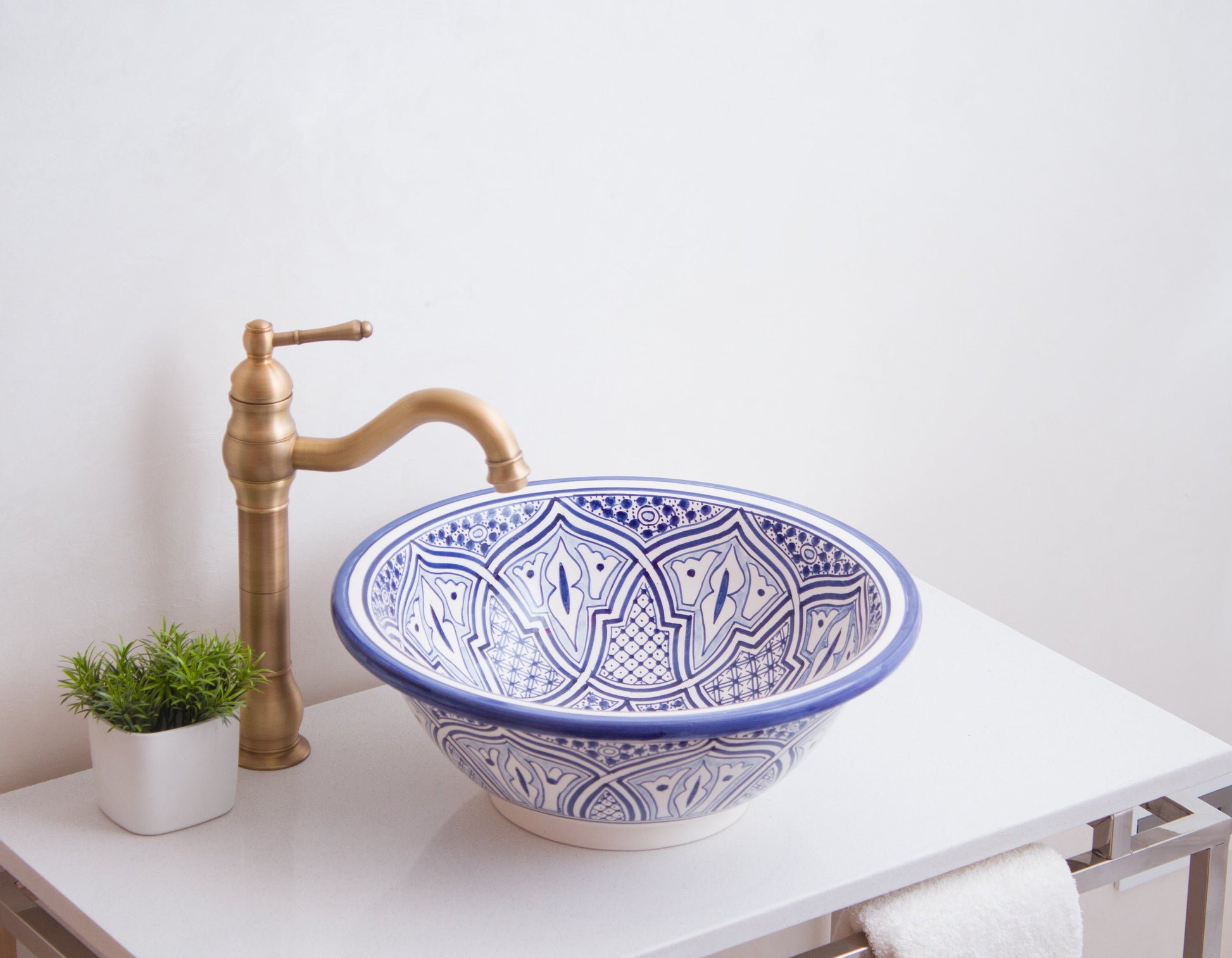 Moroccan vessel sink photographed from side angle with curved brass faucet in contemporary bathroom setting