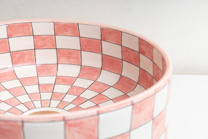 Close-up interior detail of ceramic vessel sink showing pink and white checker pattern with drain opening and curved bowl walls