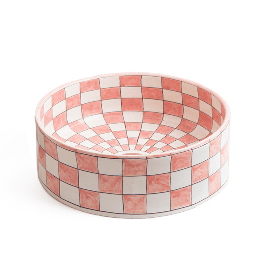 Three-quarter perspective view of ceramic vessel sink with pink and white checker pattern on white background showing complete bowl shape