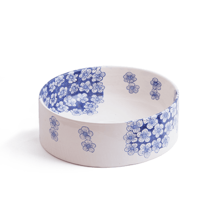 Three-quarter perspective view of ceramic vessel sink with blue flower motifs on white background showing complete bowl shape and decorative pattern