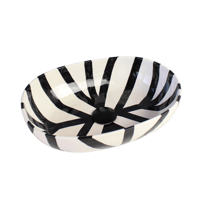 Overhead view of oval ceramic sink showing hand painted black radiating stripe pattern
