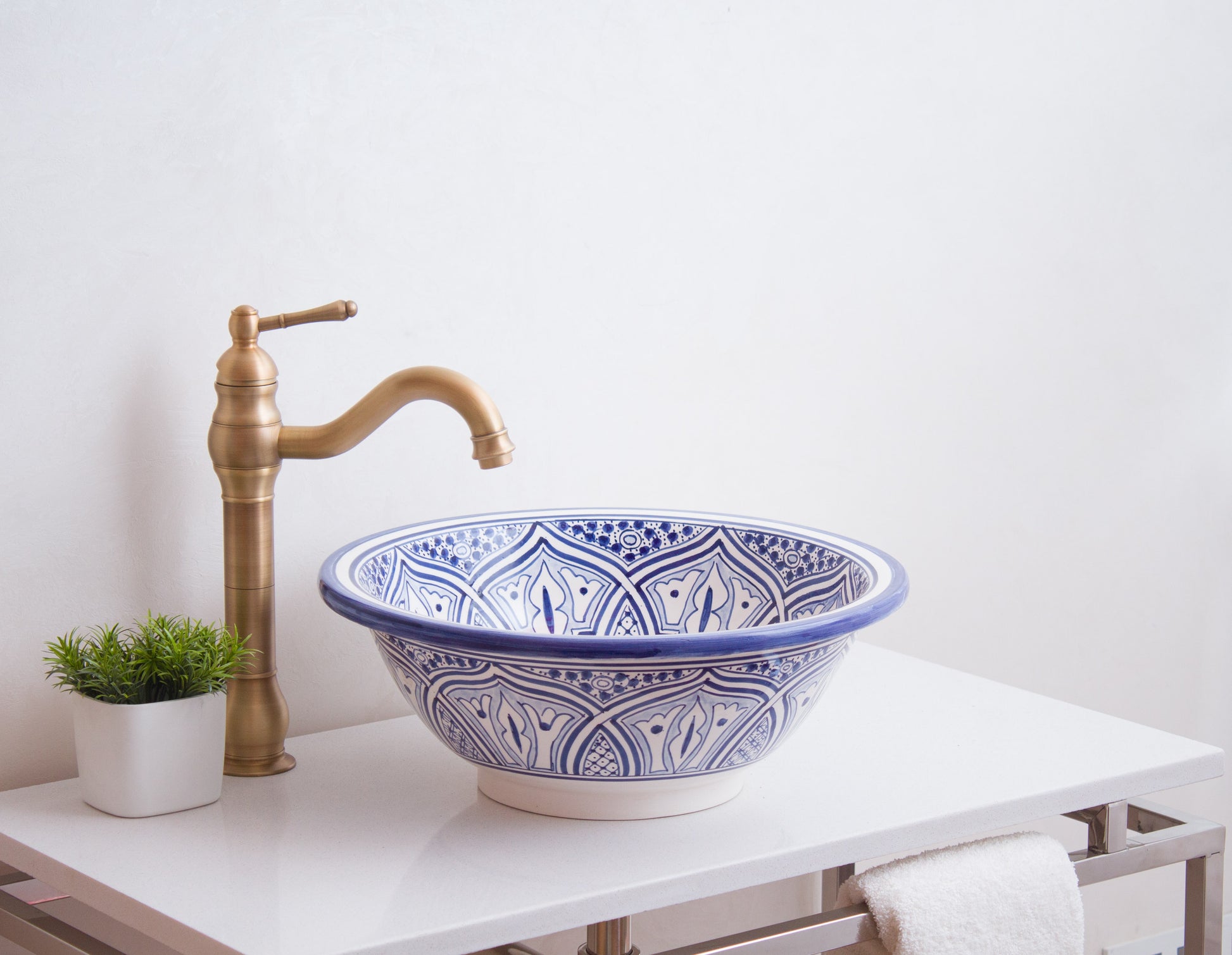 Blue and white ceramic basin styled with brass traditional faucet and decorative plant on modern vanity