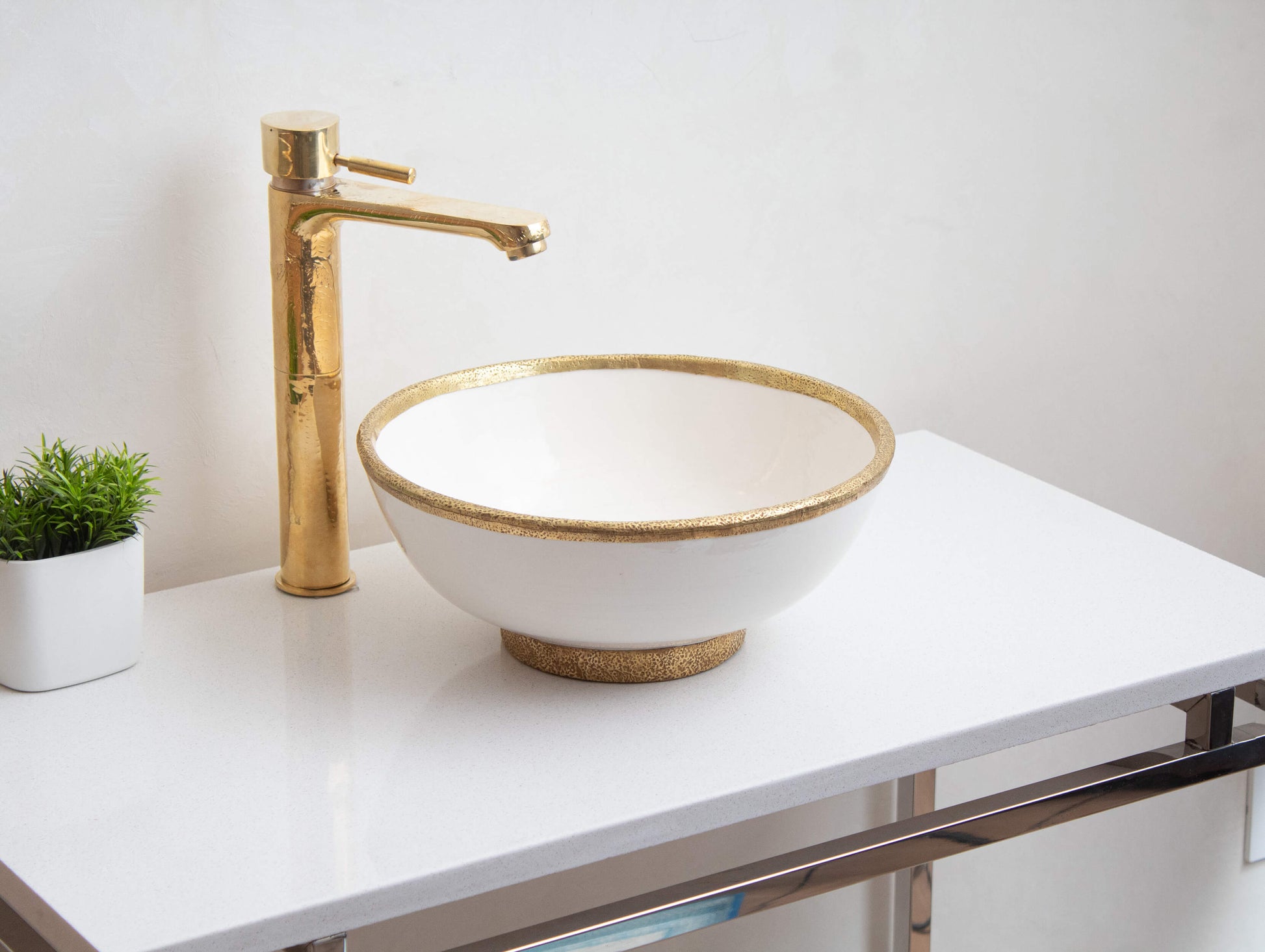 Handcrafted Moroccan white ceramic bowl sink on a marble counter and a brass faucet